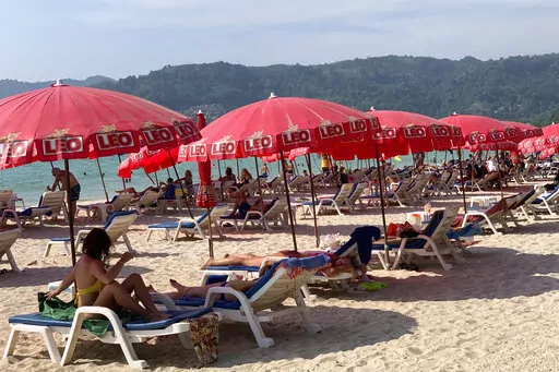 Tourists lounge under umbrellas along Patong Beach in Phuket, Thailand, Friday, March 11, 2022. Thousands of Russian tourists are stranded in Thailand's beach resorts because of the war in Ukraine, many unable to pay their bills or return home because of sanctions and canceled flights.  The crisis in Europe also put a crimp in recovery plans for the Southeast Asian nation’s tourism industry, which has hosted more visitors from Russia than any of its neighbors before the pandemic hit. (AP Photo
