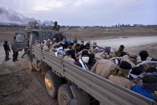 Israeli soldiers stand by a truck packed with bound and blindfolded Palestinian detainees, in Gaza, Friday, Dec. 8, 2023. The roundups have laid bare an emerging tactic in Israel's ground offensive in Gaza, experts say, as the military seeks to solidify control in evacuated areas in the north and collect intelligence about Hamas operations nearly 10 weeks after the group's deadly Oct. 7 attack on southern Israel. (AP Photo/Moti Milrod, Haaretz, File)