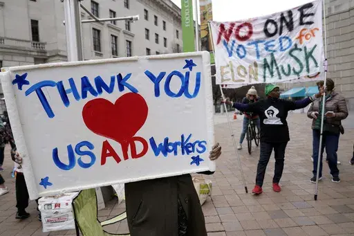 Supporters cheers the United States Agency for International Development (USAID) workers, as they carry their personal belongings after retrieving them from the USAID's headquarters in Washington, Thursday, Feb. 27, 2025. (AP Photo/Jose Luis Magana, File)
