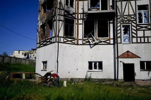 A man checks his car destroyed by attacks in Mostyshche, on the outskirts of Kyiv, Ukraine, Monday, June 6, 2022. (AP Photo/Natacha Pisarenko)