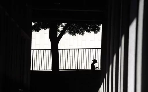 A person is silhouetted against a wall as they look down at their cell phone outside the Clara Shortridge Foltz Criminal Justice Center on July 29, 2021, in Los Angeles. With abortion now or soon to be illegal in over a dozen states and severely restricted in many more, Big Tech companies that vacuum up personal details of their users are facing new calls to limit that tracking and surveillance. One fear is that law enforcement or vigilantes could use those data troves against people seeking way