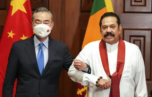 Chinese Foreign Minister Wang Yi, left, poses for media before his meeting with Sri Lankan Prime Minister Mahinda Rajapaksa in Colombo, Sri Lanka, Sunday, Jan. 9, 2022. (AP Photo/Eranga Jayawardena)