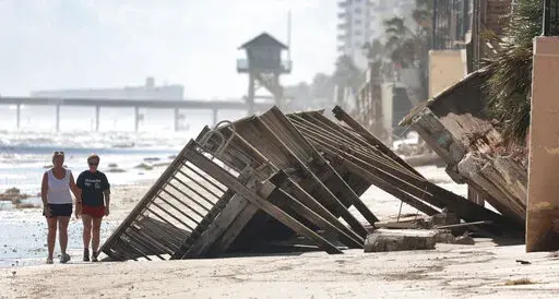 Beachgoers survey the damage Monday, Oct. 3, 2022, in Daytona Beach Shores, Fla., as hotel and condo seawalls and pool decks along the Volusia County coastline were gutted by Hurricane Ian last week. (Joe Burbank/Orlando Sentinel via AP)