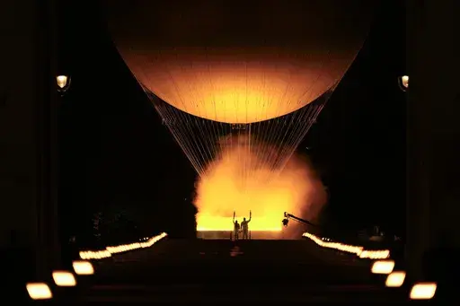 Teddy Riner and Marie-Jose Perec watch as the cauldron rises in a balloon in Paris, France, during the opening ceremony of the 2024 Summer Olympics, Friday, July 26, 2024. (AP Photo/Vadim Ghirda)