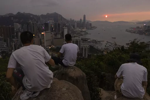 Mainland Chinese tourists look at sunset from a hill in Hong Kong, April 26, 2023. Living in Hong Kong today means juggling contradictory feelings. In 20 interviews, many said that when they focus on business indicators and everyday life, they see a recovery gathering pace after years of travel restrictions. But when it comes to anything political, the openness and freedoms that were once hallmarks of the Chinese-ruled former British colony seem permanently gone. (AP Photo/Louise Delmotte, File)