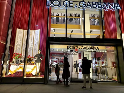 People stand outside the Dolce & Gabbana store on Fifth Avenue, Nov. 21, 2021, in New York. Dolce&Gabbana has become the first Italian fashion house to bring its beauty division in-house, a move that the CEO said Tuesday would strengthen the link between beauty and fashion, and help build inroads with younger consumers.  (AP Photo/Pamela Hassell, file)
