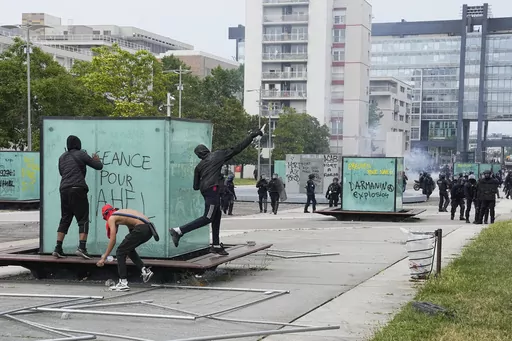 Youth throws a bottle to police forces during riots Thursday, June 29, 2023 in Nanterre, outside Paris. In all, more than 3,600 people have been detained in the unrest across France since the death of Nahel on June 27, with an average age of 17, according to the Interior Ministry. The violence left more than 800 law enforcement officers injured, French courts are working overtime to process the arrests, including opening their doors through the weekend, with fast-track hearings around an hour lo