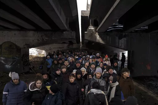 People crowd under a destroyed bridge as they try to flee, crossing the Irpin river on the outskirts of Kyiv, Ukraine, Tuesday, March 8, 2022. Russia's relentless digital assaults on Ukraine may have caused less damage than many anticipated. But most of its hacking is focused on a different goal that gets less attention but has chilling potential consequences: data collection. (AP Photo/Felipe Dana, File)