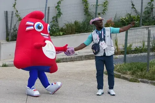 The Olympic Phryge, left, the mascot, poses with Mamadou Yero Diallo in Paris, France, ahead of the opening ceremony of the 2024 Summer Olympics, Friday, July 26, 2024. (AP Photo/Kirsty Wigglesworth)