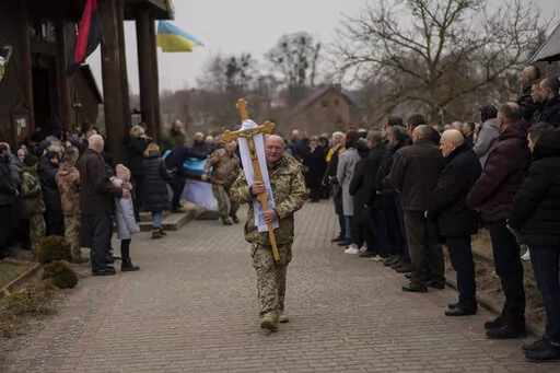 People attend a funeral ceremony for Ukrainian military servicemen Roman Rak and Mykola Mykytiuk in Starychi, western Ukraine, Wednesday, March 16, 2022. Rak and Mykytiu were killed during Sunday's Russian missile strike on a military training base in Yavoriv. (AP Photo/Bernat Armangue)
